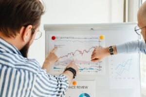 Colleagues discussing data trends on a whiteboard with graphs and charts.